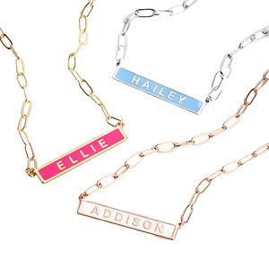 Three necklaces with chain links and rectangular name plates in different colors: pink with \“ELLIE,\“ blue with \“HAILEY,\“ and rose gold with \“ADDISON.\“