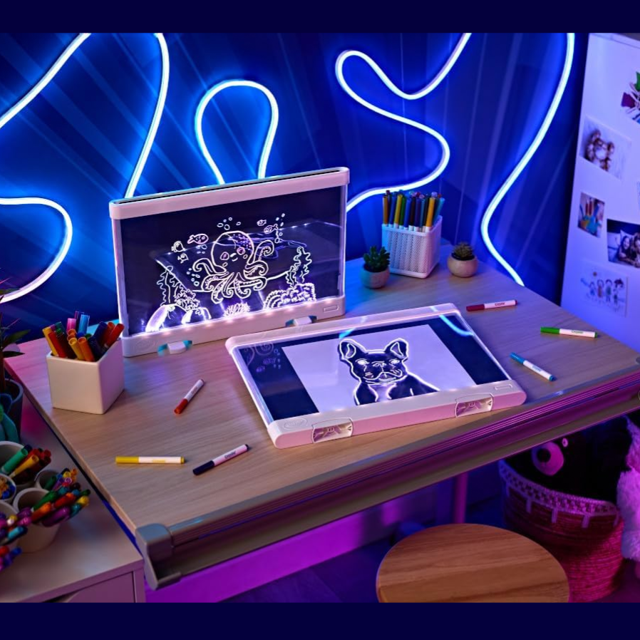 A children's drawing desk with neon lights features a foldable art board, digital drawing screen, colorful markers, and decorative plush toys.