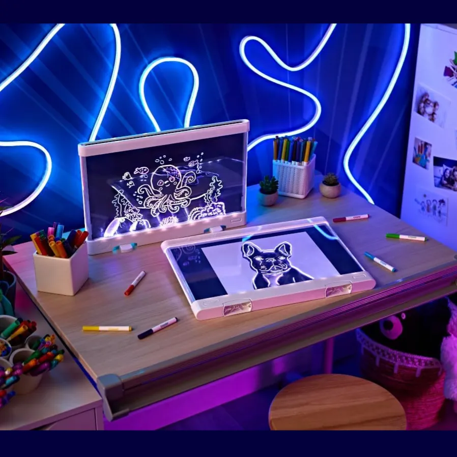 A children's drawing desk with neon lights features a foldable art board, digital drawing screen, colorful markers, and decorative plush toys.