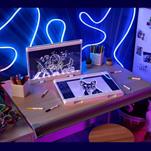A children's drawing desk with neon lights features a foldable art board, digital drawing screen, colorful markers, and decorative plush toys.