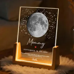 A personalized moon lamp displayed on a wooden base, featuring a moon phase from September 14th, 1990, surrounded by stars with the text \“Mommy\“ and a heartfelt message from Amelia.