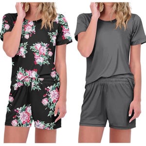 Two casual women's sleepwear sets: one features a black floral print and the other is solid gray, both with short sleeves and elastic waist shorts.