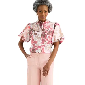 A woman wears a short-sleeved, floral-patterned blouse with puff sleeves and high-waisted, wide-leg pink pants.