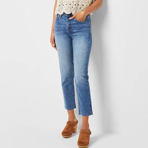 A person wearing light wash, cropped jeans paired with a lace top and brown platform shoes.