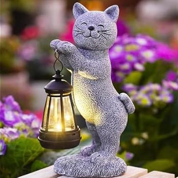 A decorative cat-shaped garden statue holding a lantern, surrounded by colorful flowers.