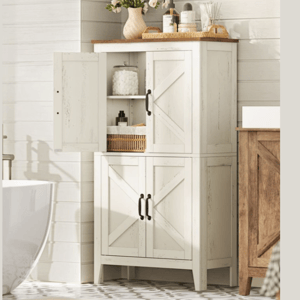 A white wooden cabinet with black handles, featuring an X-design, stands in a bathroom setting. It has three compartments with shelves, one door open revealing toiletries, and decor items like flowers and soap dispensers on top.