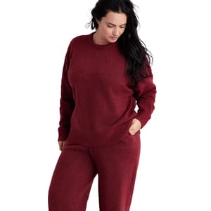 A person is wearing a burgundy sweater and matching pants.