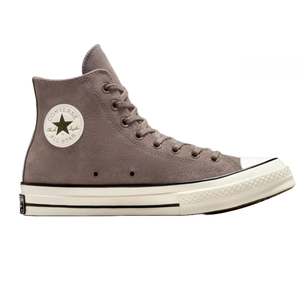 High-top Converse Chuck 70 shoes in taupe suede with a classic white rubber sole and black stripe detailing. Features include the iconic circular All Star logo patch on the side and white toe cap.