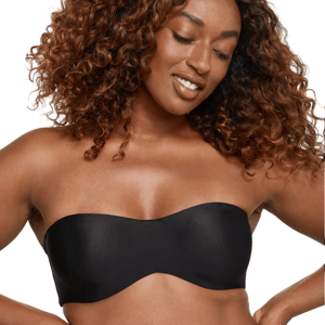 A woman with curly hair wears a black strapless bra, smiling slightly.