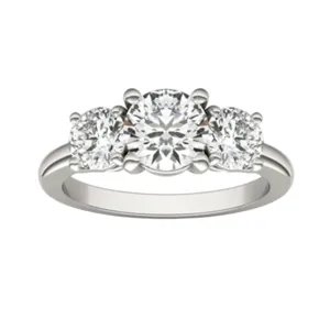 A three-stone engagement ring featuring a central round diamond flanked by two smaller round diamonds, set in a white metal band.