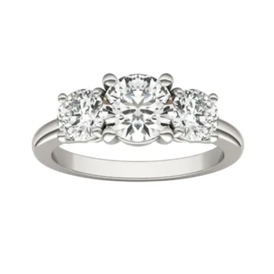A three-stone engagement ring featuring a central round diamond flanked by two smaller round diamonds, set in a white metal band.