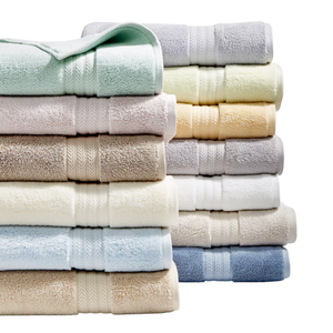 A variety of neatly stacked, colorful bath towels in pastel and neutral shades.