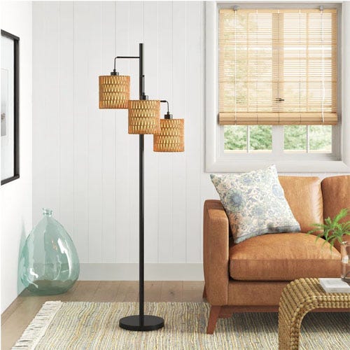 A black and tan lamp in a living room with a tan leather couch.