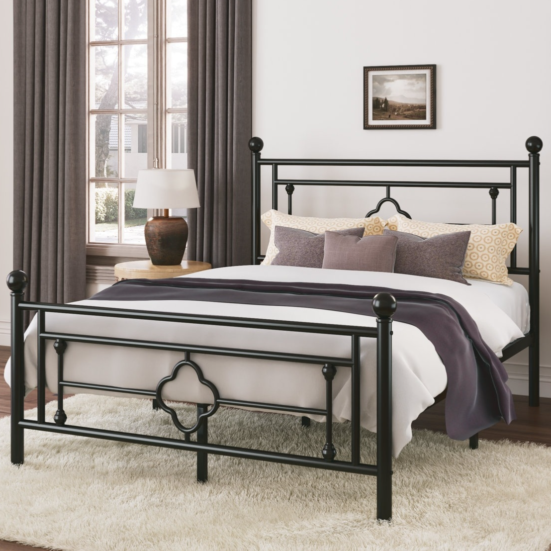 Black metal bed frame with decorative design, set in a room with a white rug, wooden nightstand, lamp, and gray curtains.