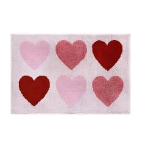 A bathroom rug featuring six hearts in shades of pink and red on a light background, arranged in two rows of three.