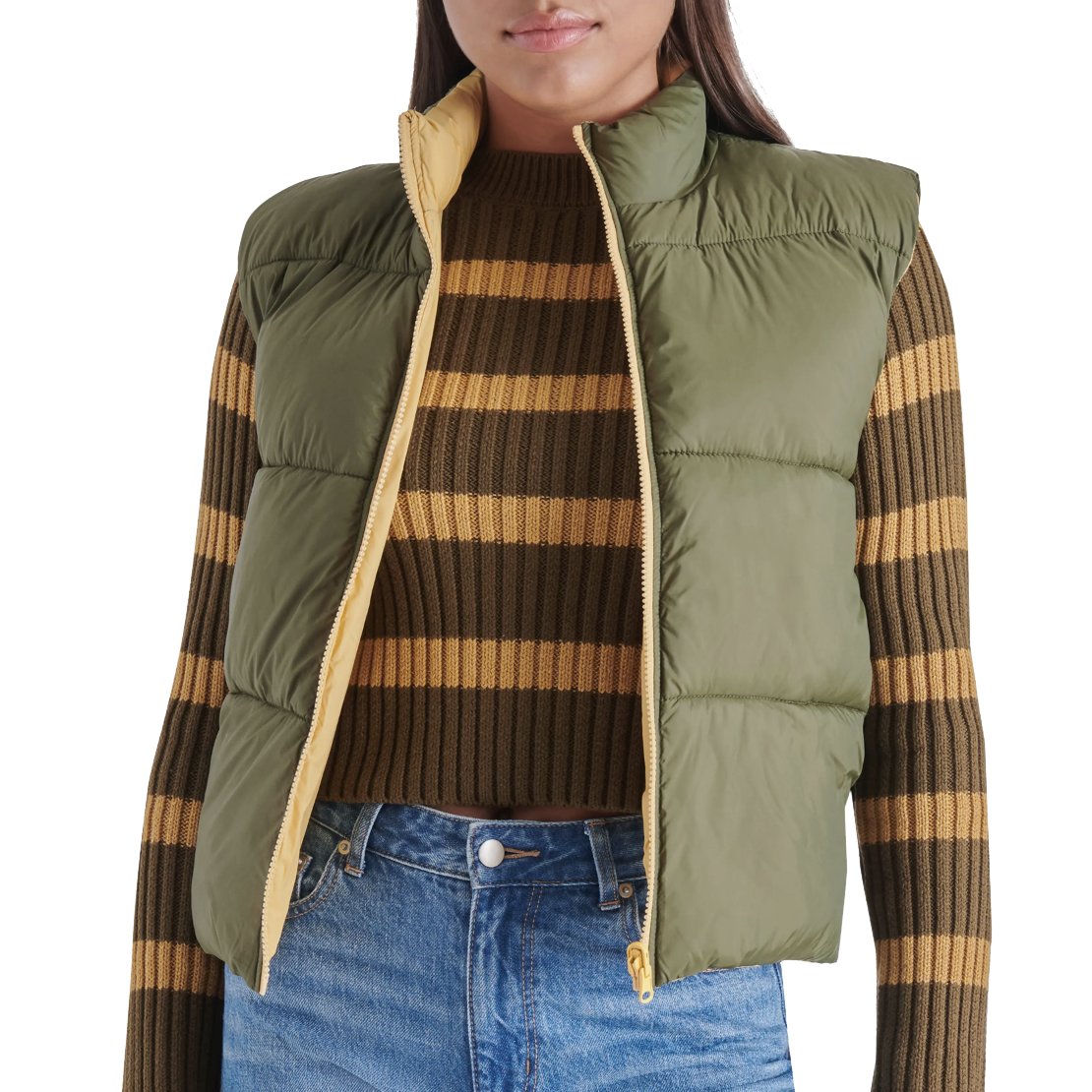 Steve Madden Reversible Puffer Vest features a green exterior with a light yellow interior, a high collar, and sleeveless design, paired with a brown and yellow striped sweater and blue jeans.