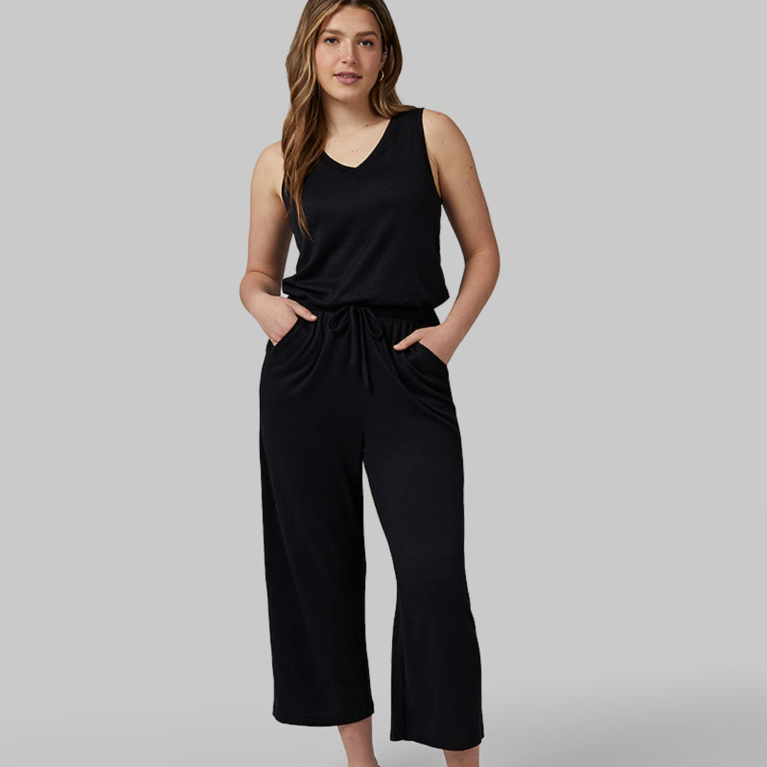 A woman is wearing a black sleeveless top and matching wide-leg trousers with a drawstring waist.