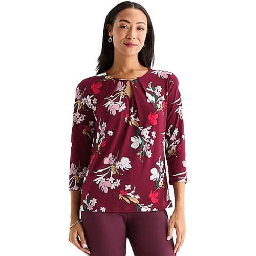 A woman is wearing a maroon floral blouse with three-quarter sleeves and matching maroon pants.