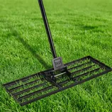 A metal lawn leveling rake with a rectangular grid head is positioned on green grass, featuring a black handle attached to a BCP branded joint.