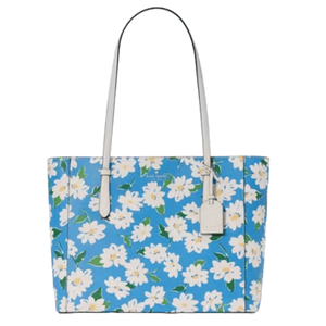 A blue Kate Spade tote adorned with a white floral print features long white handles and an attached tag.