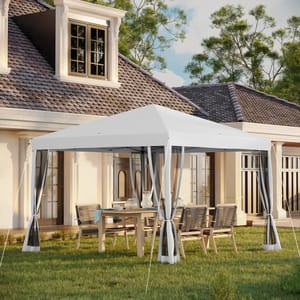 A white canopy tent with clear side panels is set up over a wooden outdoor dining table with chairs on a grassy lawn in front of a house.