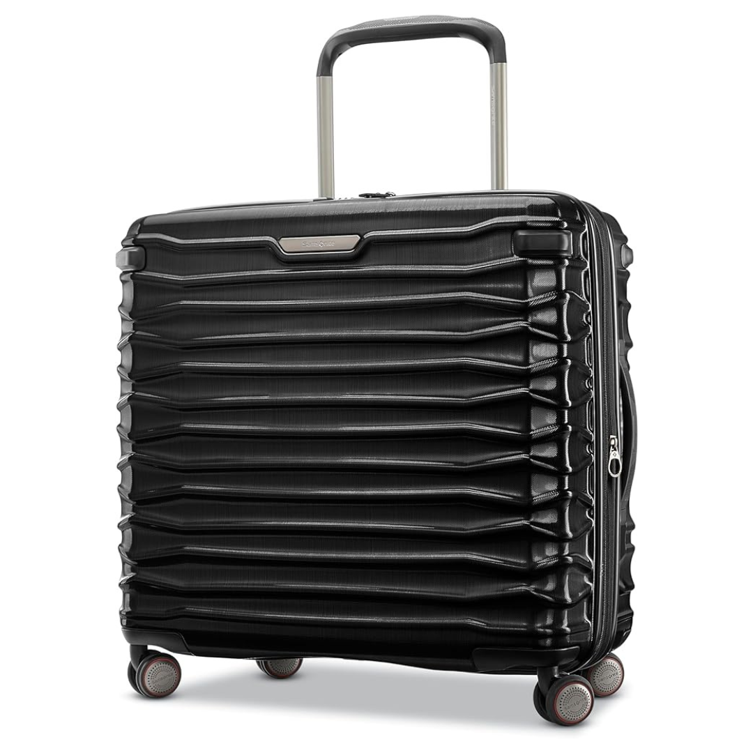 A black hard-shell suitcase with a textured, horizontal ribbed design, featuring four multi-directional spinner wheels and a telescopic handle.