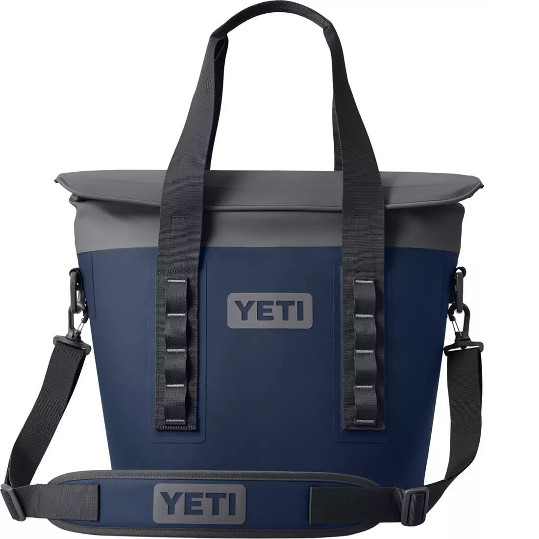 YETI cooler bag with a shoulder strap, dark blue in color with a contrasting gray top. Features durable handles and a clip-on strap for easy carrying.