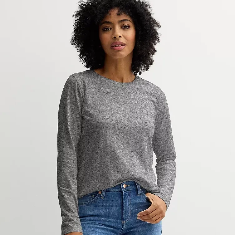 A woman wearing a long-sleeved heather gray top and blue jeans.