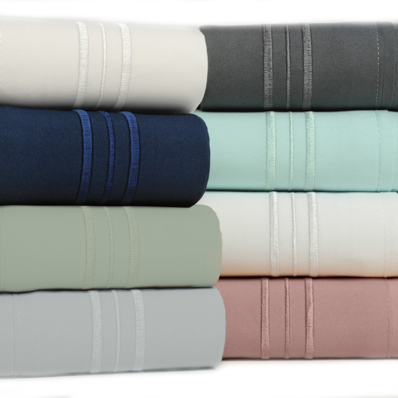 A stack of rolled bamboo sheet sets in six colors: cream, gray, navy, light turquoise, sage, and rose, each featuring decorative triple-stitched bands.