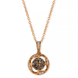 A gold-tone necklace featuring a round pendant with a central cluster of dark stones surrounded by white accent stones on an intricate open design.