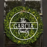 A decorative wreath with the text \“The Garcia Family\“ features a lush, green foliage design, embellished with a twine bow for a personal touch.