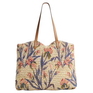 Woven tote bag with floral embroidery in blue, pink, and green, featuring brown leather straps.