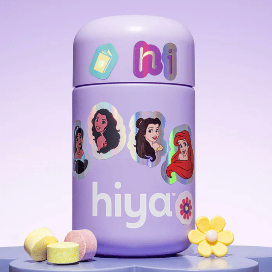 A purple container labeled \“hiya\“ is adorned with stickers of animated princess characters. It is accompanied by colorful tablets and a yellow flower-shaped accessory.