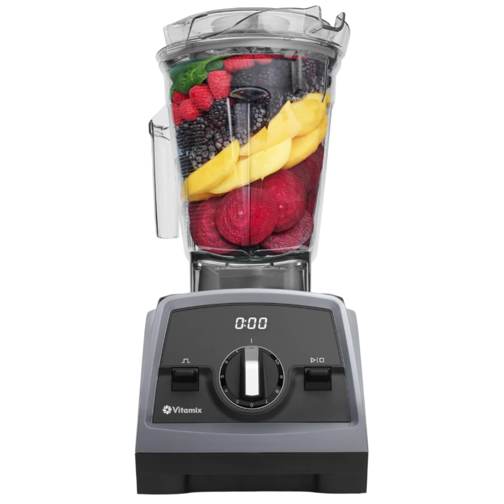 A Vitamix blender filled with various fruits and vegetables, including leafy greens, raspberries, blackberries, mango slices, and beets.