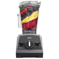 A Vitamix blender filled with various fruits and vegetables, including leafy greens, raspberries, blackberries, mango slices, and beets.