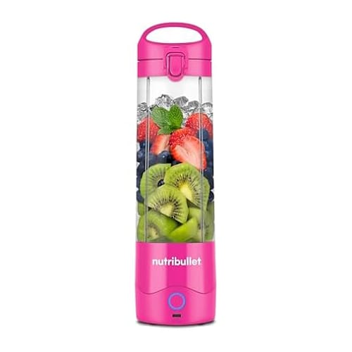 A pink NutriBullet portable blender filled with ice, strawberries, blueberries, kiwi slices, and mint leaves.