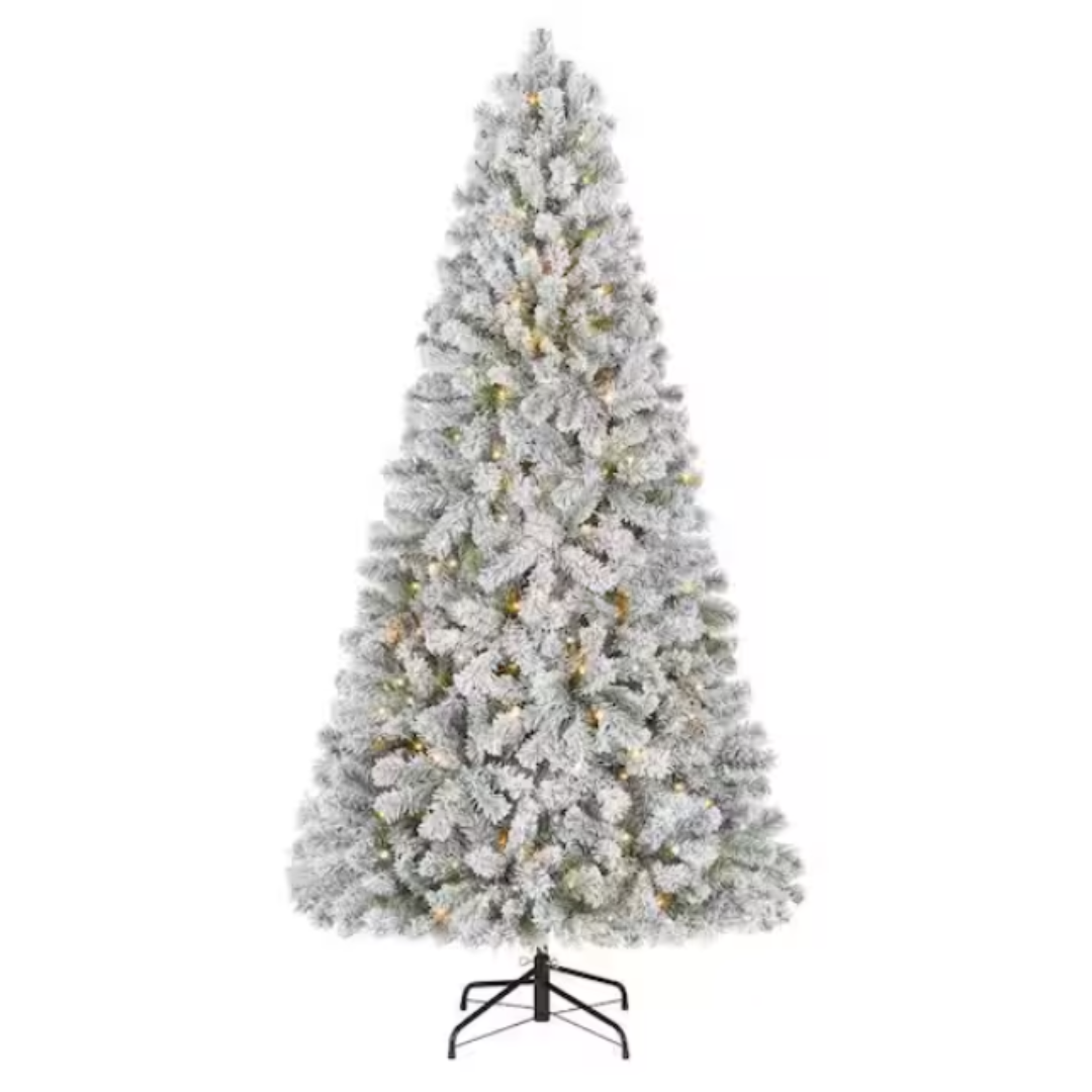A snowy artificial Christmas tree with built-in warm white lights on a black stand.