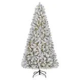 A snowy artificial Christmas tree with built-in warm white lights on a black stand.