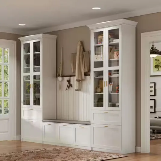 White built-in storage units with glass-front cabinets and a bench. Hooks hold coats and accessories, integrating practical storage with elegant design.