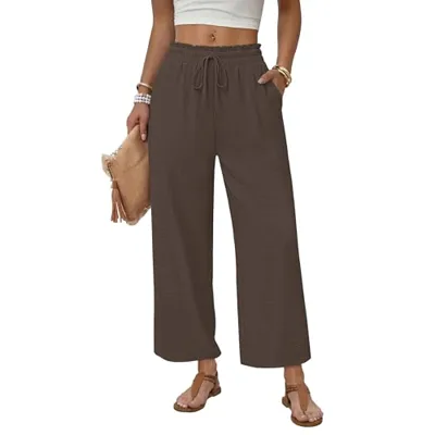 The image shows a person wearing brown wide-leg pants with an elastic waistband and drawstring. They are accessorized with sandals, bracelets, and a clutch.