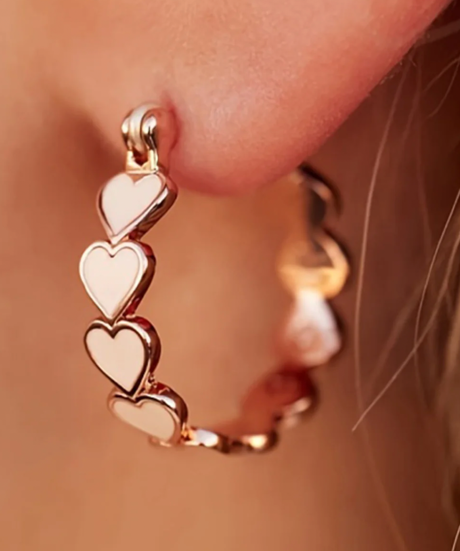 Rose gold hoop earrings featuring a series of small, linked heart shapes along the circle.