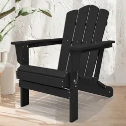 A black Adirondack chair is placed on a light wood floor next to potted plants and a white vase, set against a textured white wall.
