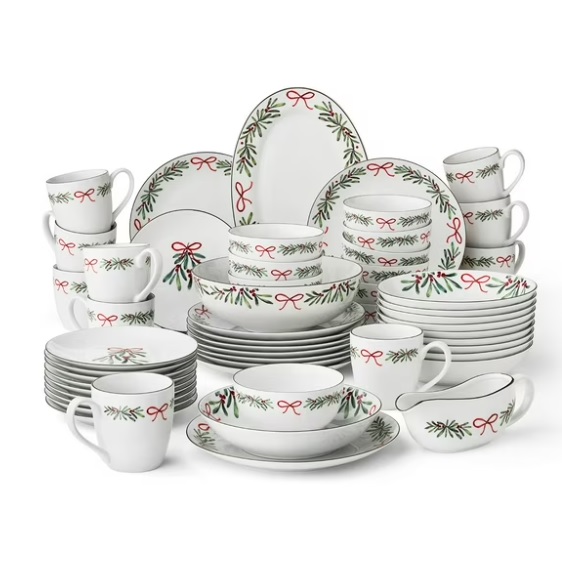 Set of holiday-themed dinnerware with red and green adornments, including plates, bowls, mugs, and serving pieces, featuring ribbon and evergreen designs.