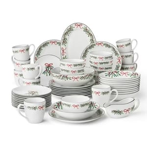 Set of holiday-themed dinnerware with red and green adornments, including plates, bowls, mugs, and serving pieces, featuring ribbon and evergreen designs.