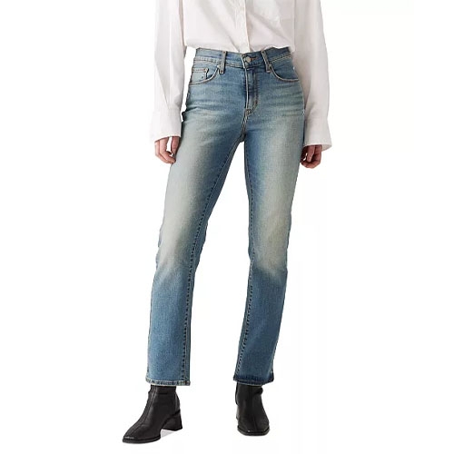 A person is wearing straight-leg jeans with a light blue wash, paired with a white button-up shirt and black boots.