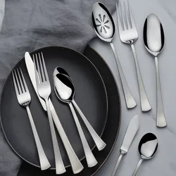 A set of stainless steel flatware includes forks, knives, and spoons arranged on two dark plates and a gray cloth.