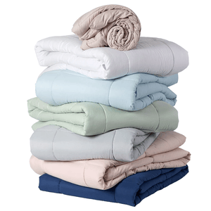 A stack of folded comforters in various colors, including beige, white, blue, green, gray, pink, and navy.