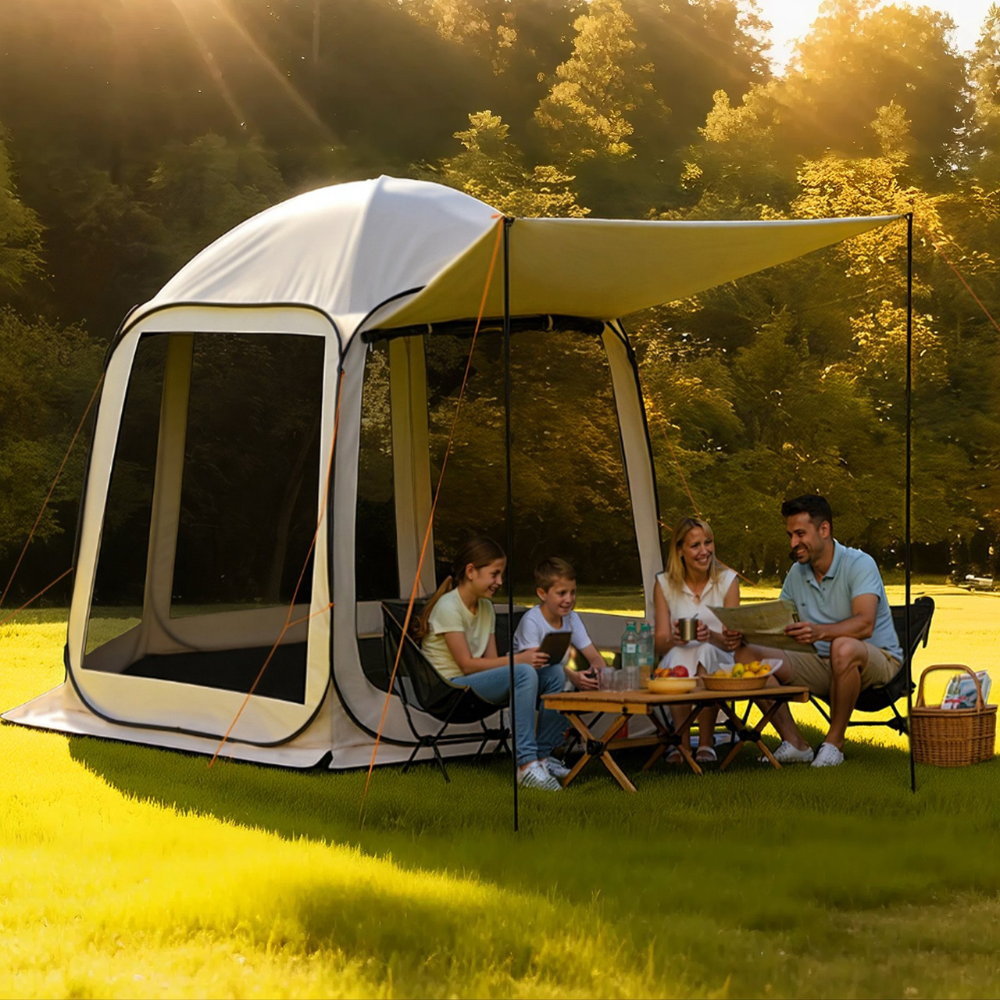 A family enjoys a picnic under a dome-shaped tent with a mesh opening and an extended canopy. They sit on folding chairs around a small table with fruit and drinks in a grassy, sunlit outdoor setting.