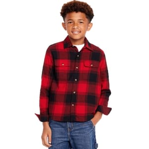 A young boy is wearing a red and black plaid button-up shirt with two chest pockets, paired with blue jeans.
