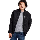 A man wearing a black quilted jacket over a gray shirt with blue denim jeans.